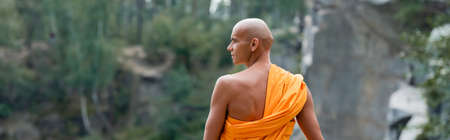 back view of buddhist monk looking away while meditating outdoors, bannerの写真素材