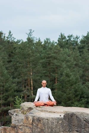 buddhist meditating in lotus pose with closed eyes outdoorsの写真素材