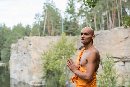 buddhist looking away while meditating with praying hands outdoorsの写真素材