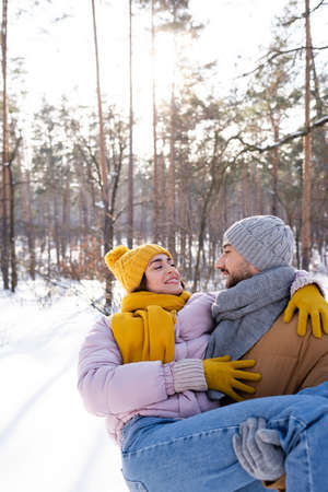 Smiling man lifting girlfriend in winter parkの写真素材