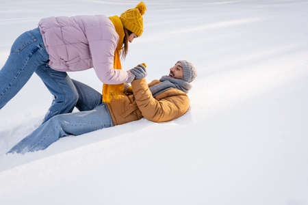 Positive couple in warm clothes playing on snow outdoorsの写真素材