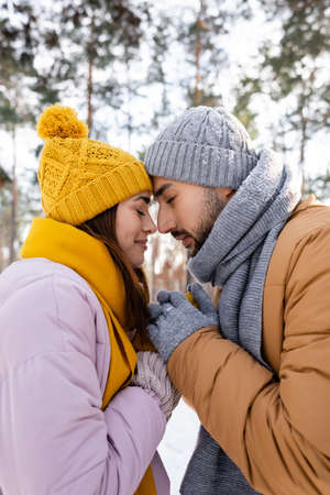 Side view of couple in knitted hats holding hands in winter parkの写真素材