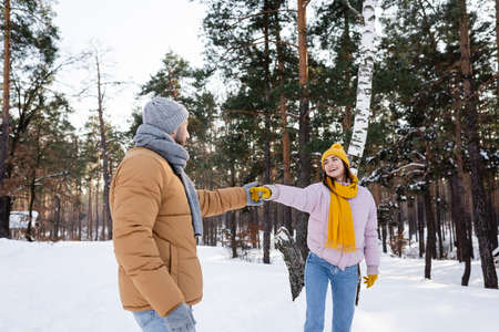 Smiling woman holding hand of boyfriend in winter parkの写真素材