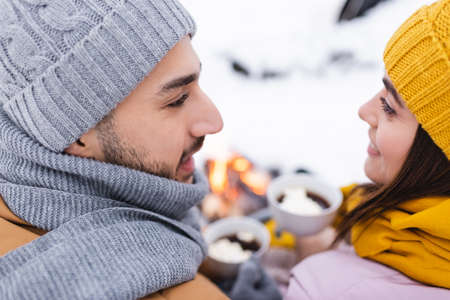 Smiling couple in knitted hats looking at each other in winter parkの写真素材