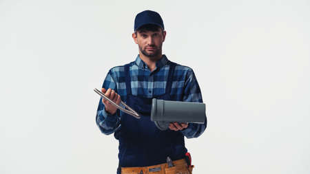 Plumber in overalls and cap holding pipes isolated on whiteの写真素材