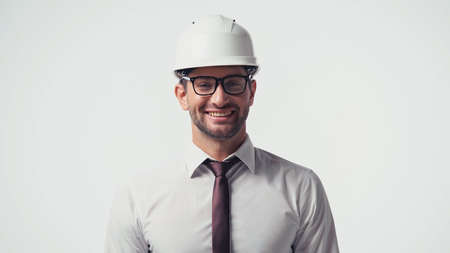 Architect in shirt, eyeglasses and hardhat smiling at camera isolated on whiteの写真素材