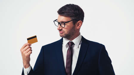 Businessman in formal wear and eyeglasses looking at credit card isolated on whiteの写真素材
