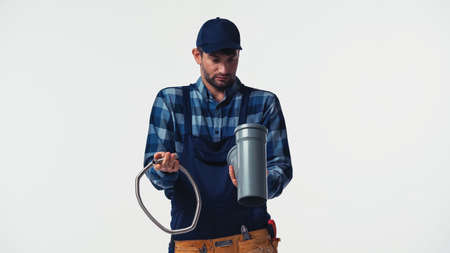 Repairman with tool belt looking at pipes isolated on whiteの写真素材