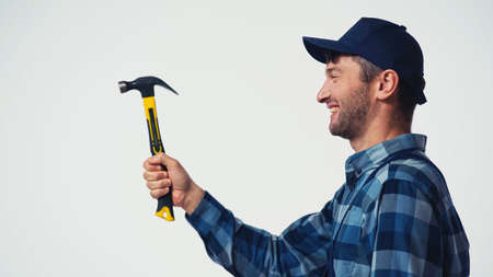Side view of cheerful workman holding hammer isolated on white