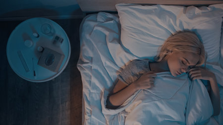 Top view of woman sleeping near pills, water and nasal spray on bedside tableの写真素材