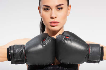 brunette young sportswoman in boxing gloves isolated on gray