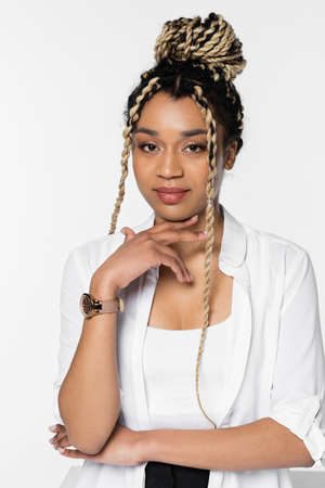 stylish african american businesswoman with hand near chin looking at camera isolated on white
