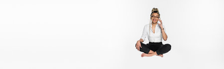 happy african american businesswoman levitating in lotus pose while talking on smartphone isolated on white, bannerの写真素材