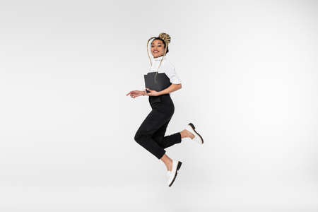 cheerful african american businesswoman looking at camera while levitating with paper folder...