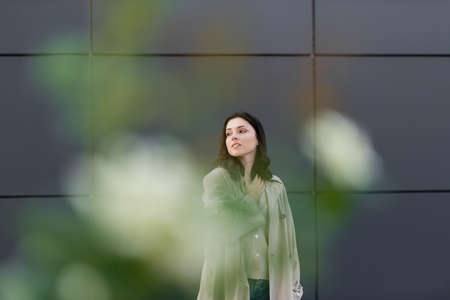 young woman looking away while holding hand on chest on blurred foregroundの写真素材