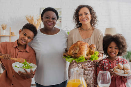 Smiling african american family with food celebrating thanksgiving at homeの写真素材