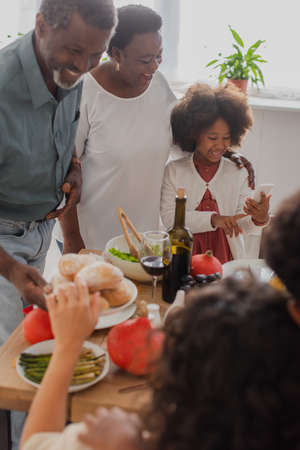African american kid using smartphone near grandparents and thanksgiving dinner
