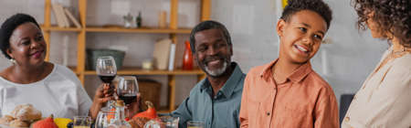 African american family looking at woman during thanksgiving celebration, banner