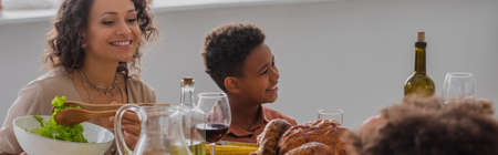 African american mother and son sitting near thanksgiving dinner, bannerの写真素材