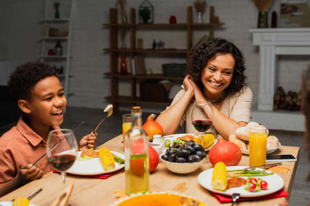 happy african american mother and son smiling during thanksgiving dinnerの写真素材