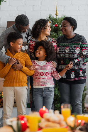 smiling african american family holding hands during christmas celebration at homeの写真素材