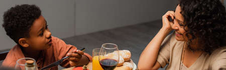 happy african american woman smiling near son having thanksgiving dinner, bannerの写真素材