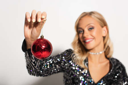 closed up view of christmas ball in hand of blurred woman in shiny blouse on whiteの写真素材