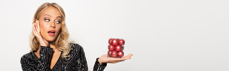 astonished and elegant woman with set of christmas balls isolated on white, bannerの写真素材