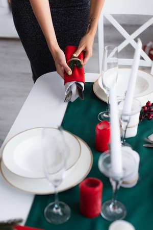 partial view of woman holding cutlery wrapped in festive napkins while serving tableの写真素材
