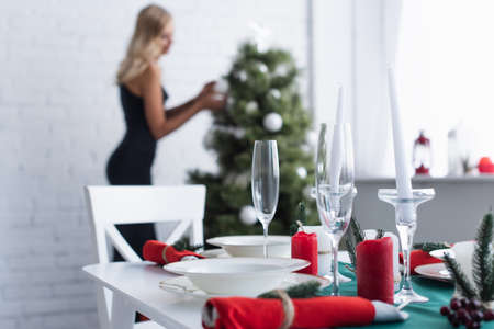 selective focus of served table near woman decorating christmas tree on blurred backgroundの写真素材