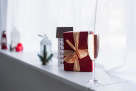 selective focus of red gift box near blurred decorative house model on windowsillの写真素材