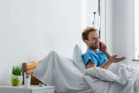 cheerful man talking on smartphone while gesturing in hospitalの写真素材