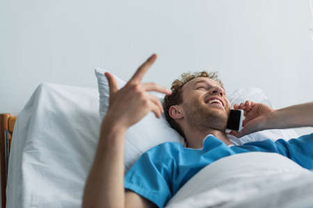 happy patient talking on smartphone while lying in hospital bedの写真素材