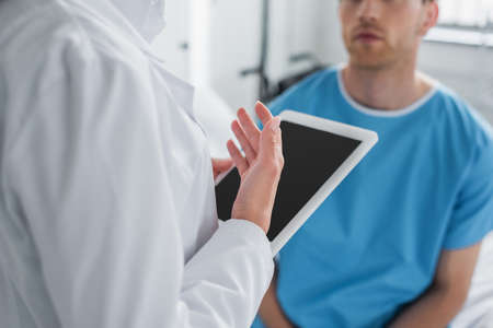 cropped view of doctor in white coat holding digital tablet near patientの写真素材