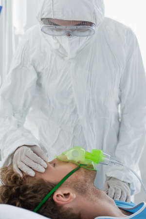 doctor in personal protective equipment examining patient in oxygen maskの写真素材