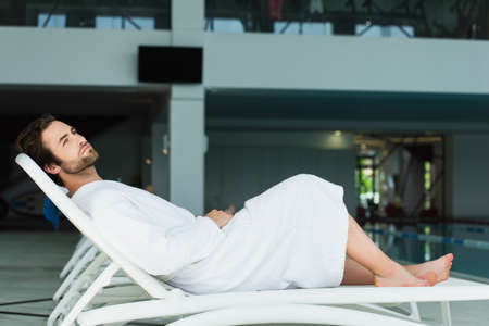 Young man relaxing on deck chair in spa centerの写真素材