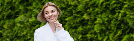 Cheerful woman in bathrobe standing outdoors, banner