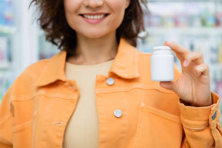 cropped view of tattooed woman smiling while holding bottle with pills in drugstoreの写真素材