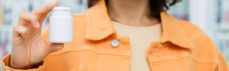 partial view of woman holding bottle with pills in drugstoreの写真素材