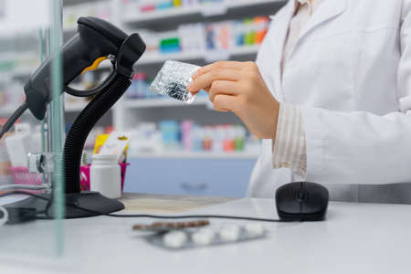 cropped view of pharmacist holding blister pack near scanner in drugstoreの写真素材