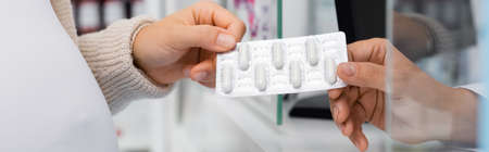 cropped view of pharmacist giving blister pack with medication to customer, bannerの写真素材