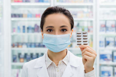 apothecary in medical mask holding blister pack with medicationの写真素材