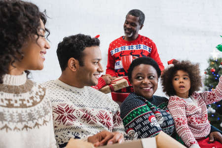 african american family smiling while talking in living roomの写真素材