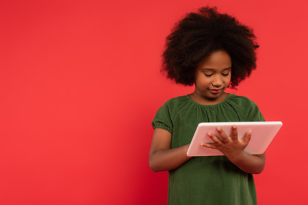 African american child using digital tablet isolated on redの写真素材