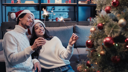 cheerful african american couple holding sparklers near christmas treeの写真素材