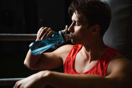 thirsty sportsman drinking water from sports bottle with closed eyes