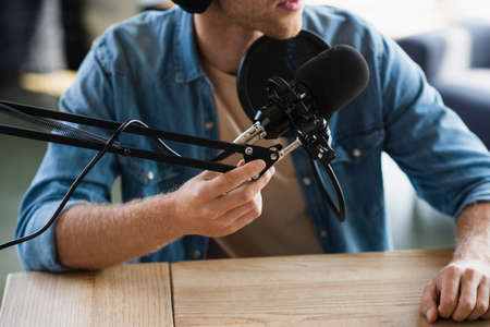 cropped view of influencer touching scissor arm near microphone while making podcast in studioの写真素材