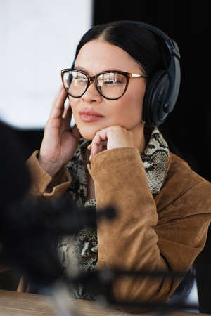 asian radio host in glasses and headphones looking awayの写真素材
