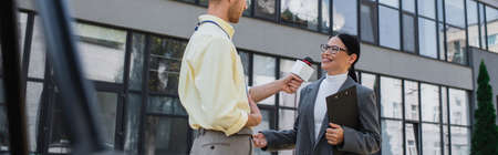 newscaster holding microphone and taking interview of cheerful asian businesswoman in glasses...