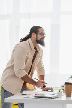 thoughtful hispanic architect looking away while working at homeの写真素材